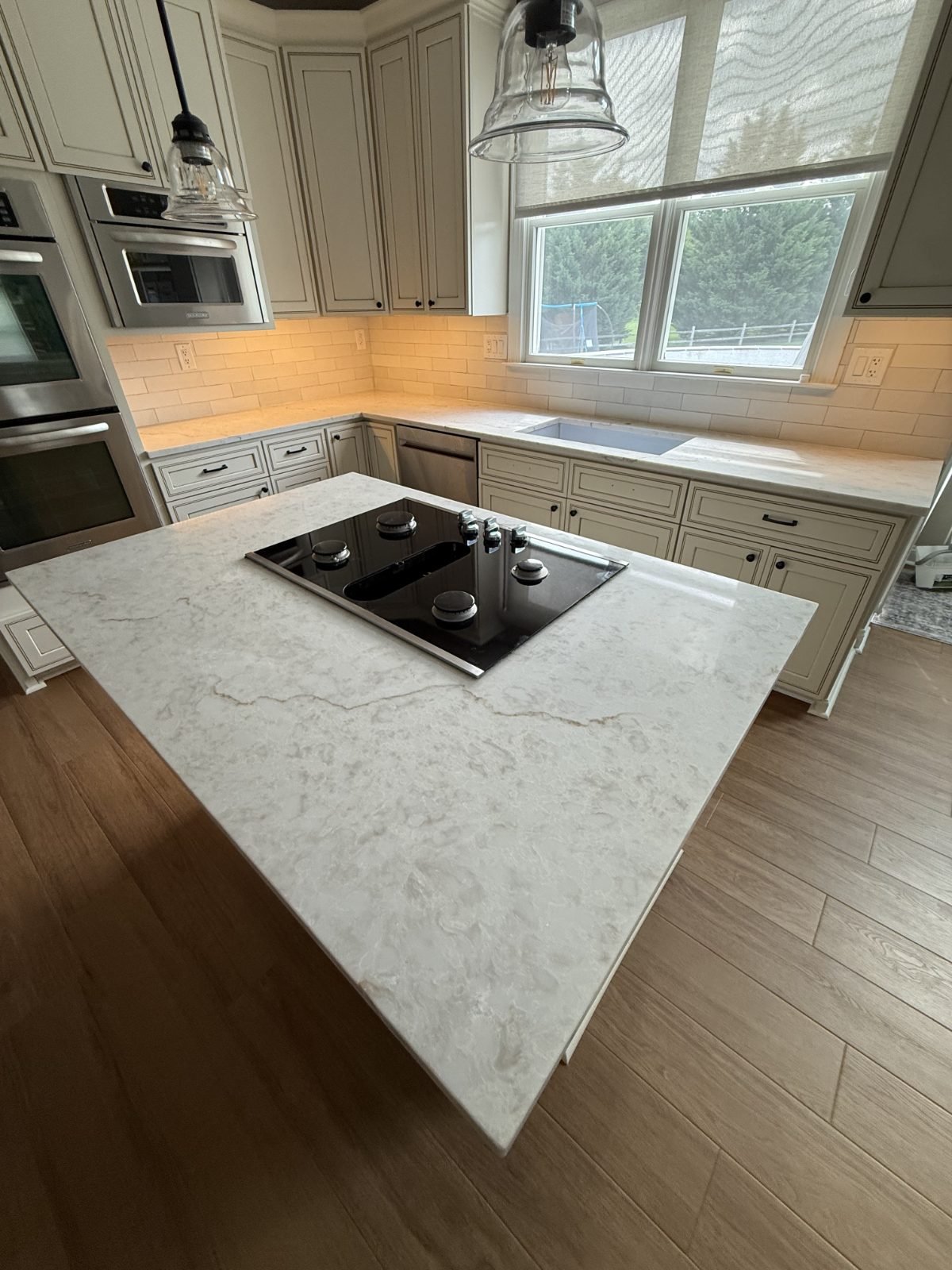 Island with a built-in cooktop under pendant lighting